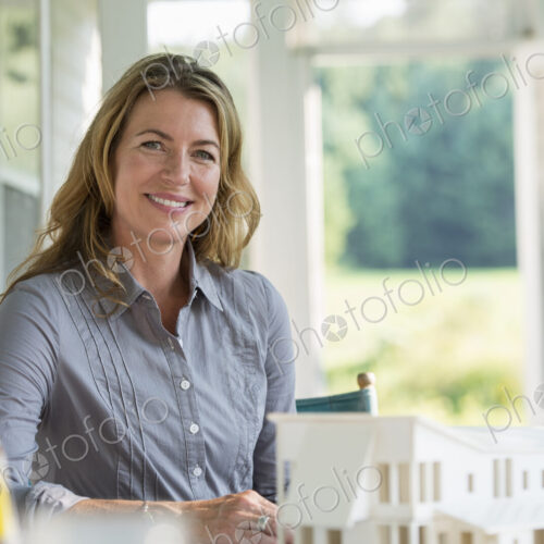 A farmhouse kitchen. A model of a house on the table. Designing a house. A woman… A farmhouse kitchen. A model of a house on the table. Designing a house. A woman…