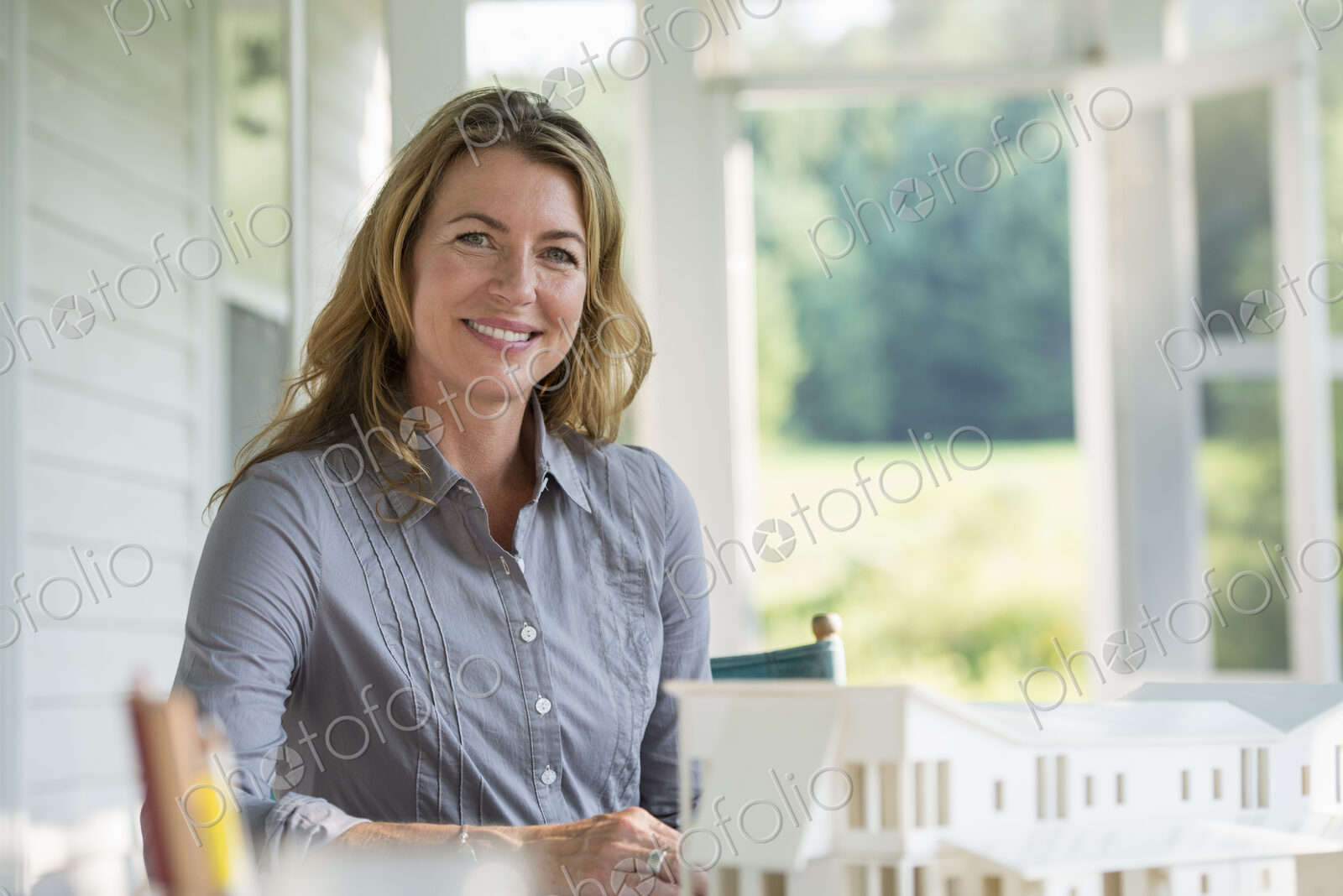 A farmhouse kitchen. A model of a house on the table. Designing a house. A woman…