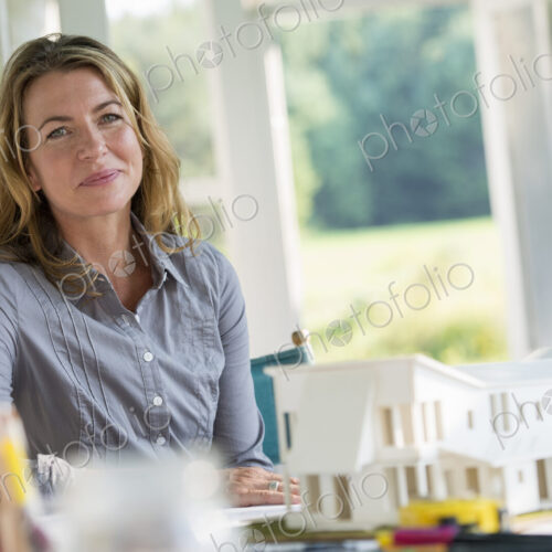 A farmhouse kitchen. A model of a house on the table. Designing a house. A woman… A farmhouse kitchen. A model of a house on the table. Designing a house. A woman…