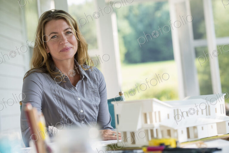 A farmhouse kitchen. A model of a house on the table. Designing a house. A woman…