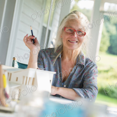A farmhouse kitchen. A model of a house on the table. Designing a house. A woman… A farmhouse kitchen. A model of a house on the table. Designing a house. A woman…