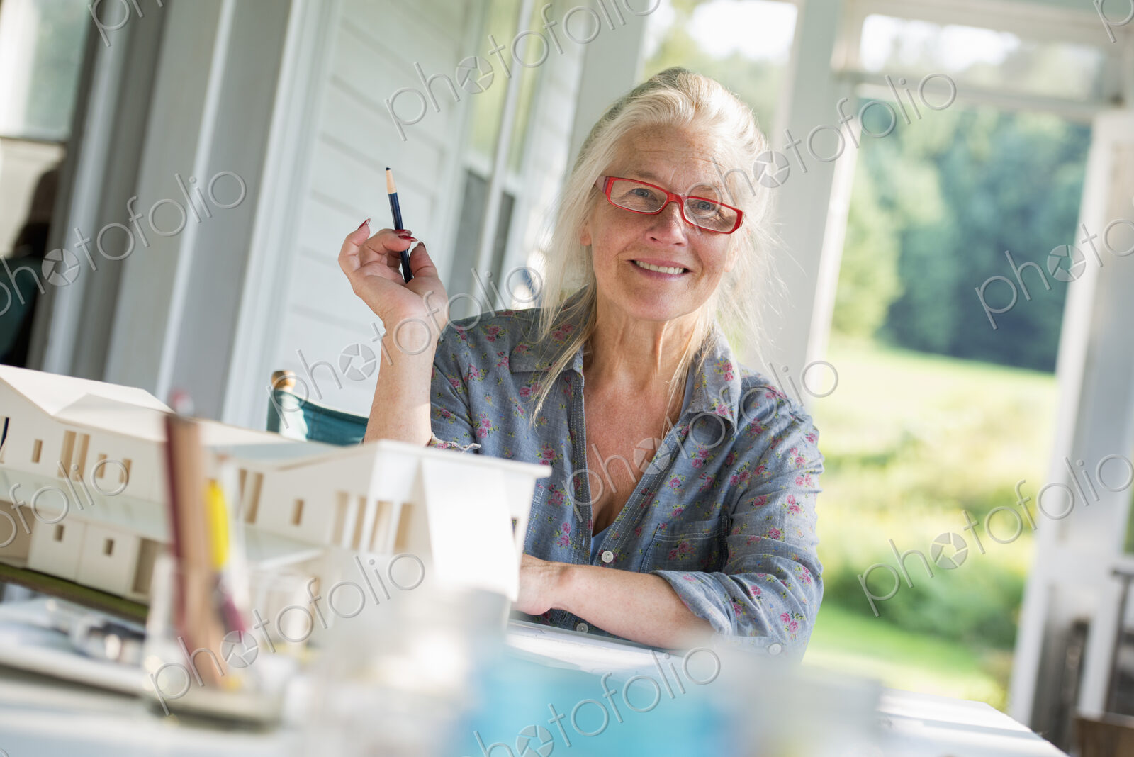 A farmhouse kitchen. A model of a house on the table. Designing a house. A woman…