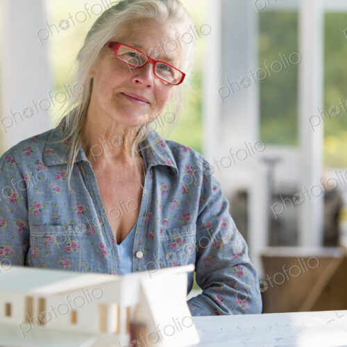 A farmhouse kitchen. A model of a house on the table. Designing a house. A woman… A farmhouse kitchen. A model of a house on the table. Designing a house. A woman…