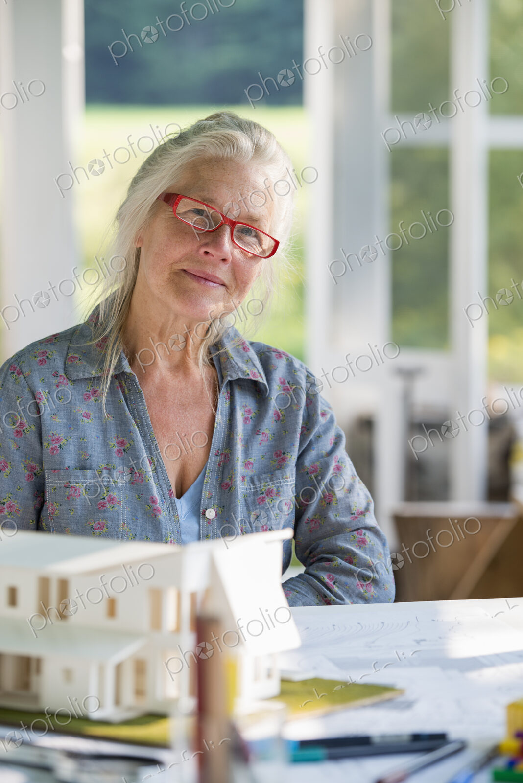 A farmhouse kitchen. A model of a house on the table. Designing a house. A woman…