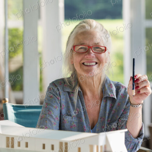 A farmhouse kitchen. A model of a house on the table. Designing a house. A woman… A farmhouse kitchen. A model of a house on the table. Designing a house. A woman…