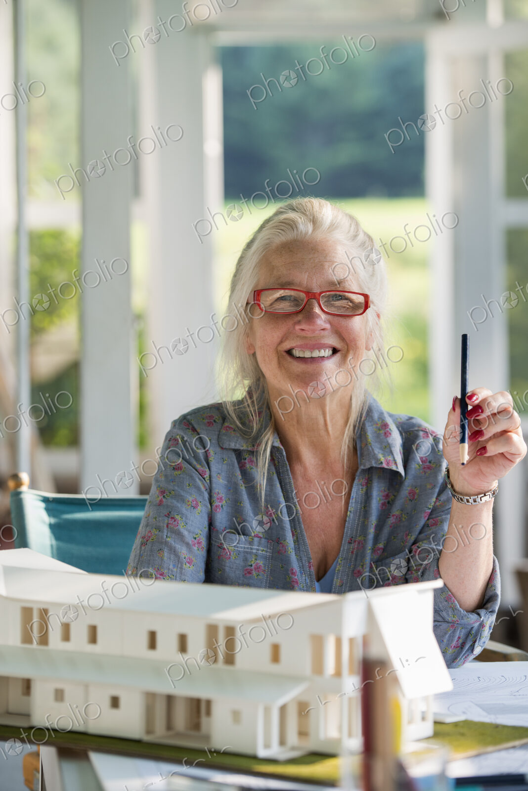 A farmhouse kitchen. A model of a house on the table. Designing a house. A woman…