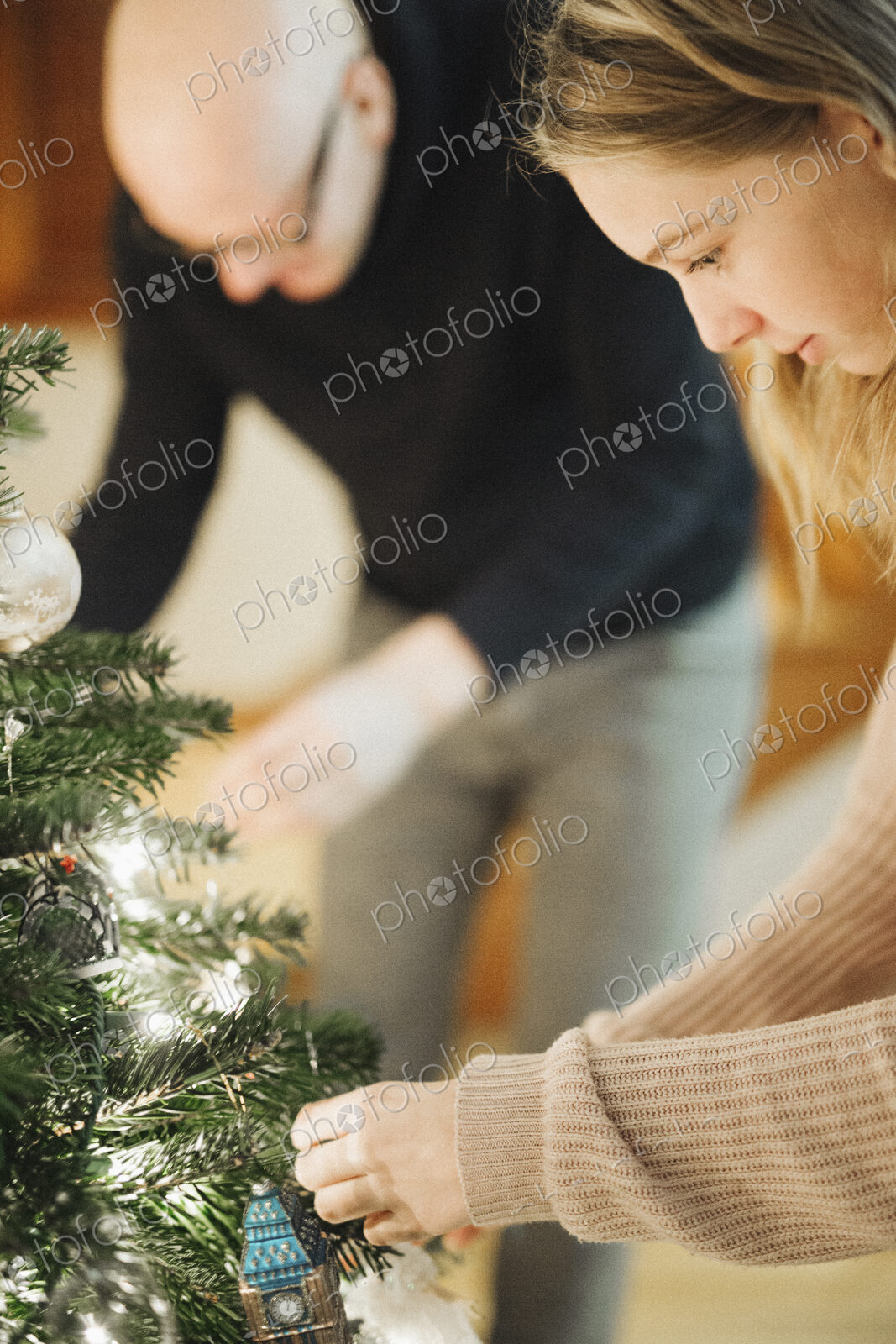 A father and daughter decorating a Christmas tree.