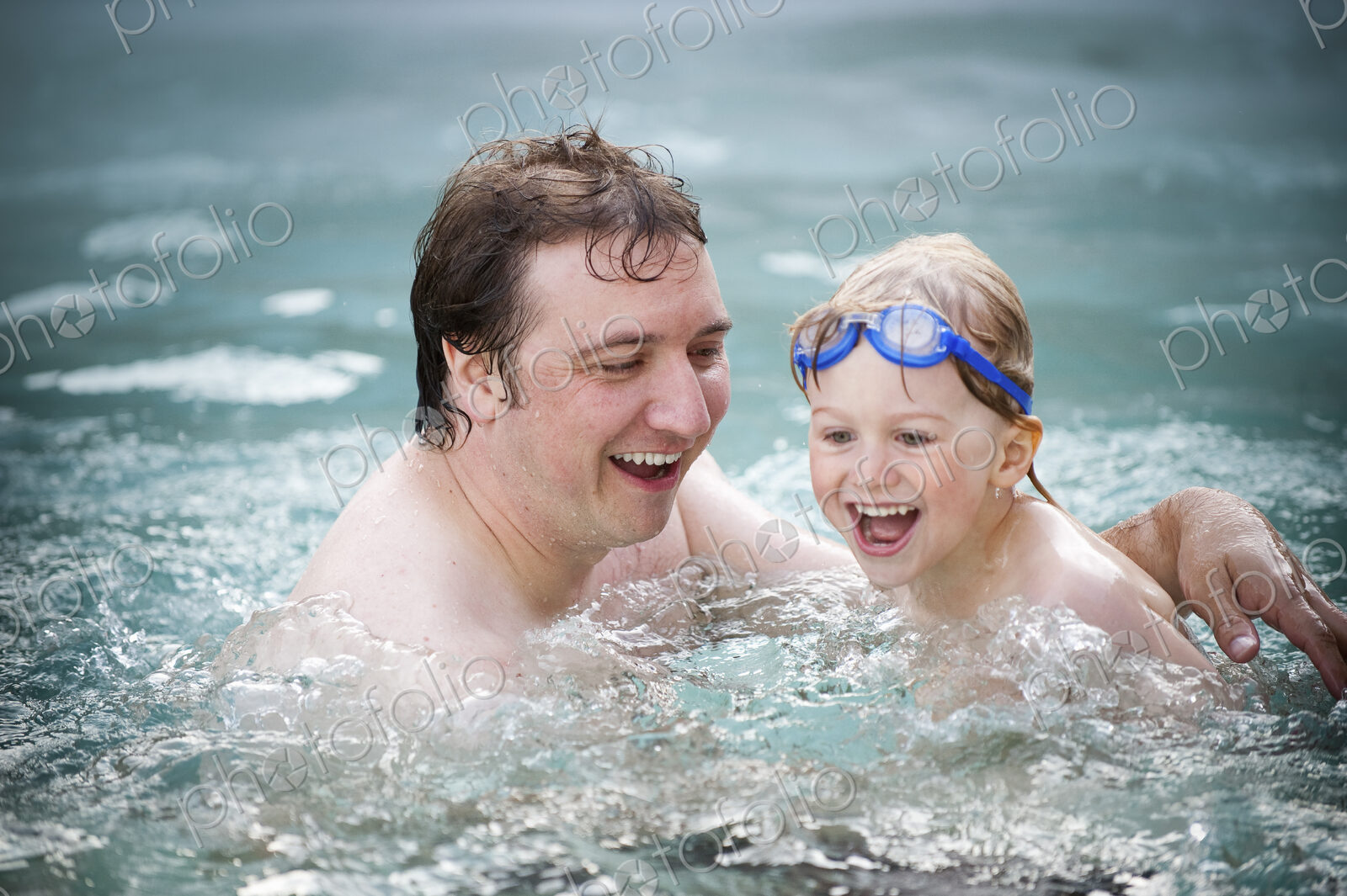 A father and son in a swimming pool, swimming.