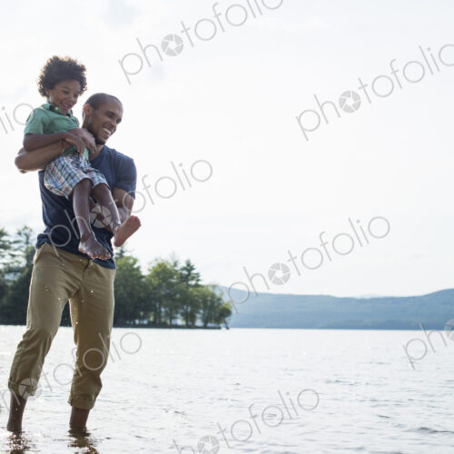 A father and son on a lake shore in summer.