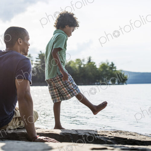 A father and son on a lake shore in summer. A father and son on a lake shore in summer.
