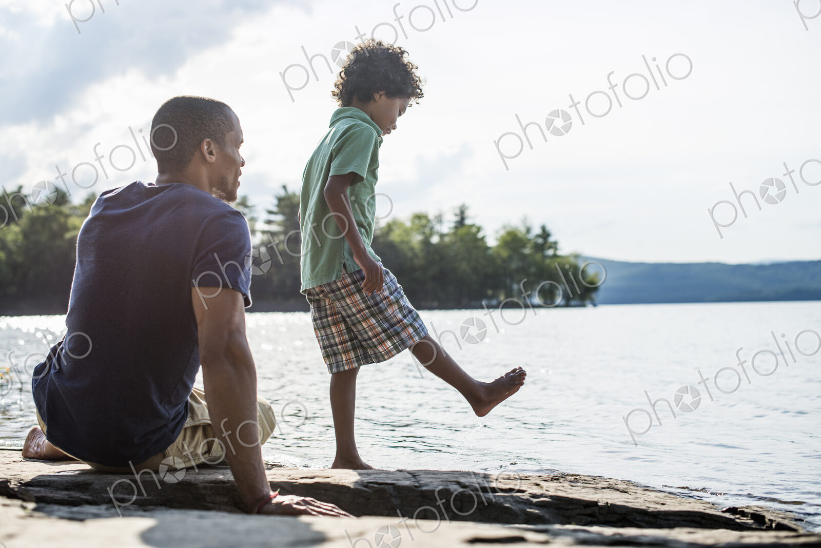 A father and son on a lake shore in summer.