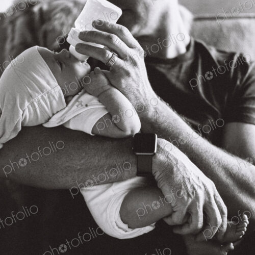 A father cradling a small baby and bottle feeding him. A father cradling a small baby and bottle feeding him.