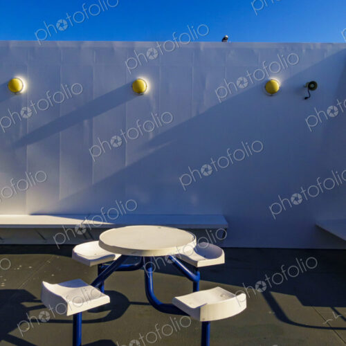 A ferry deck, fixed seating and a round table. A ferry deck, fixed seating and a round table.