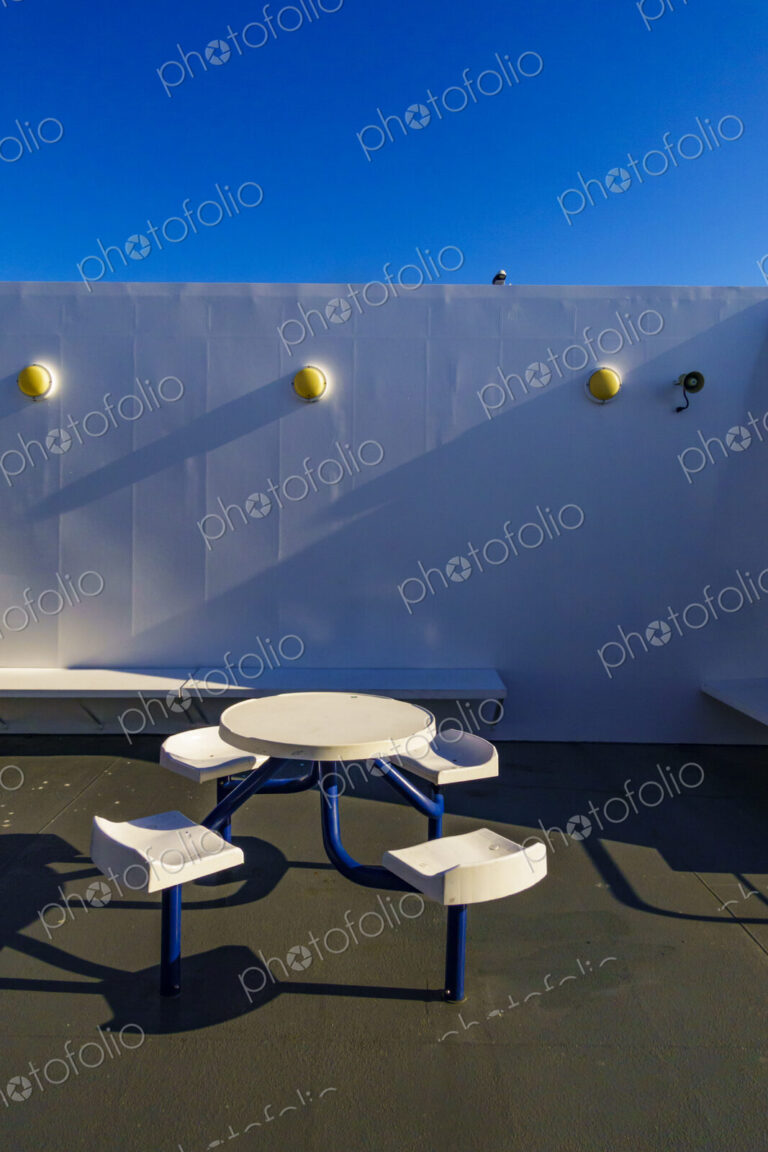A ferry deck, fixed seating and a round table.