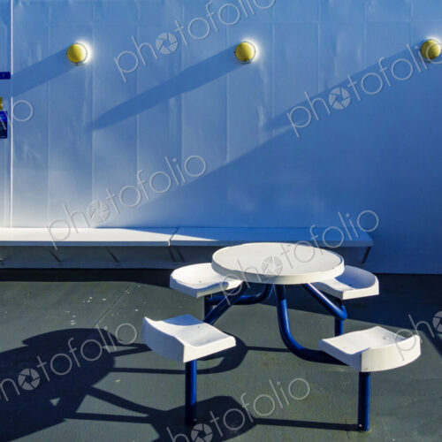 A ferry deck, fixed seating and a round table. A ferry deck, fixed seating and a round table.