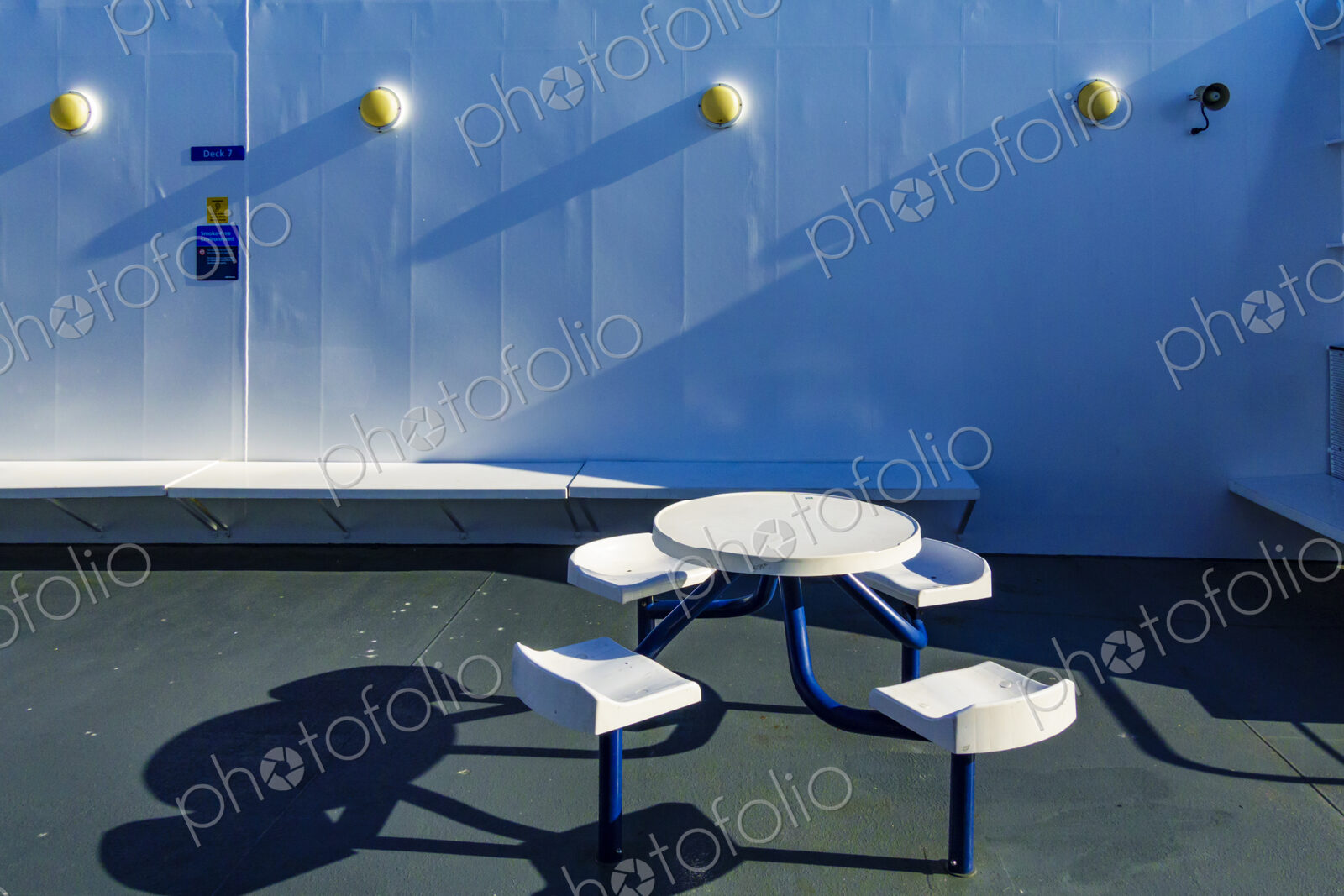 A ferry deck, fixed seating and a round table.