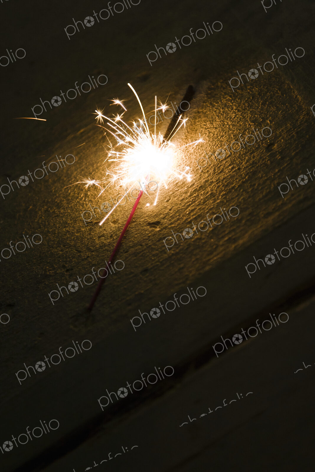 A firework sparkler on the ground, on a sandy beach.