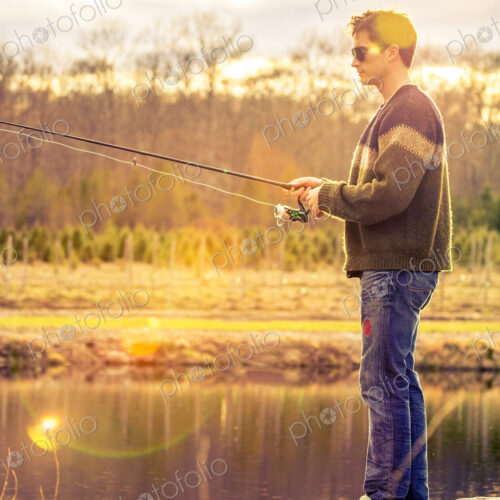 A fisherman standing on the edge of a lake.