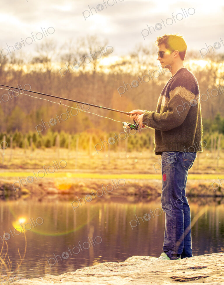 A fisherman standing on the edge of a lake.