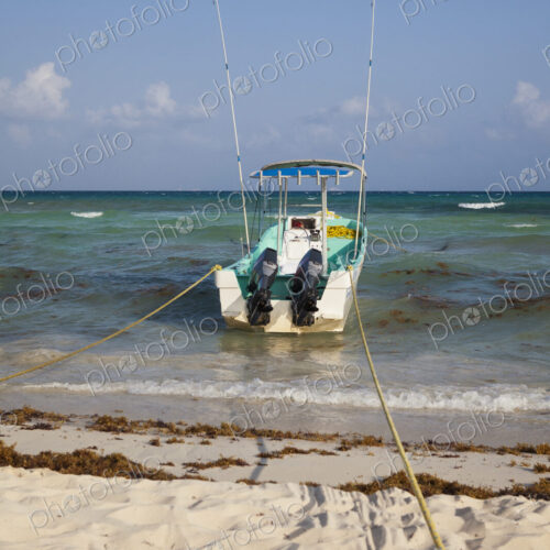 A fishing boat anchored at the edge of the water,on the beach A fishing boat anchored at the edge of the water,on the beach