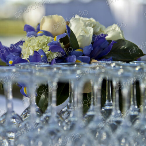 A formal party dining table laid out with glasses, silver flatware, candles and flowers.