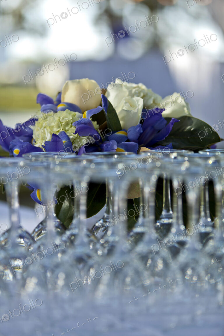 A formal party dining table laid out with glasses, silver flatware, candles and flowers.