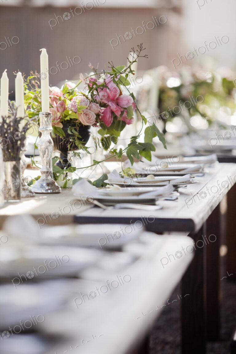 A formal wedding breakfast table, laid for a feast. Fresh flowers in the centre.