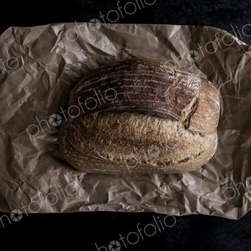 A fresh loaf of baked bread on a brown paper bag. A fresh loaf of baked bread on a brown paper bag.