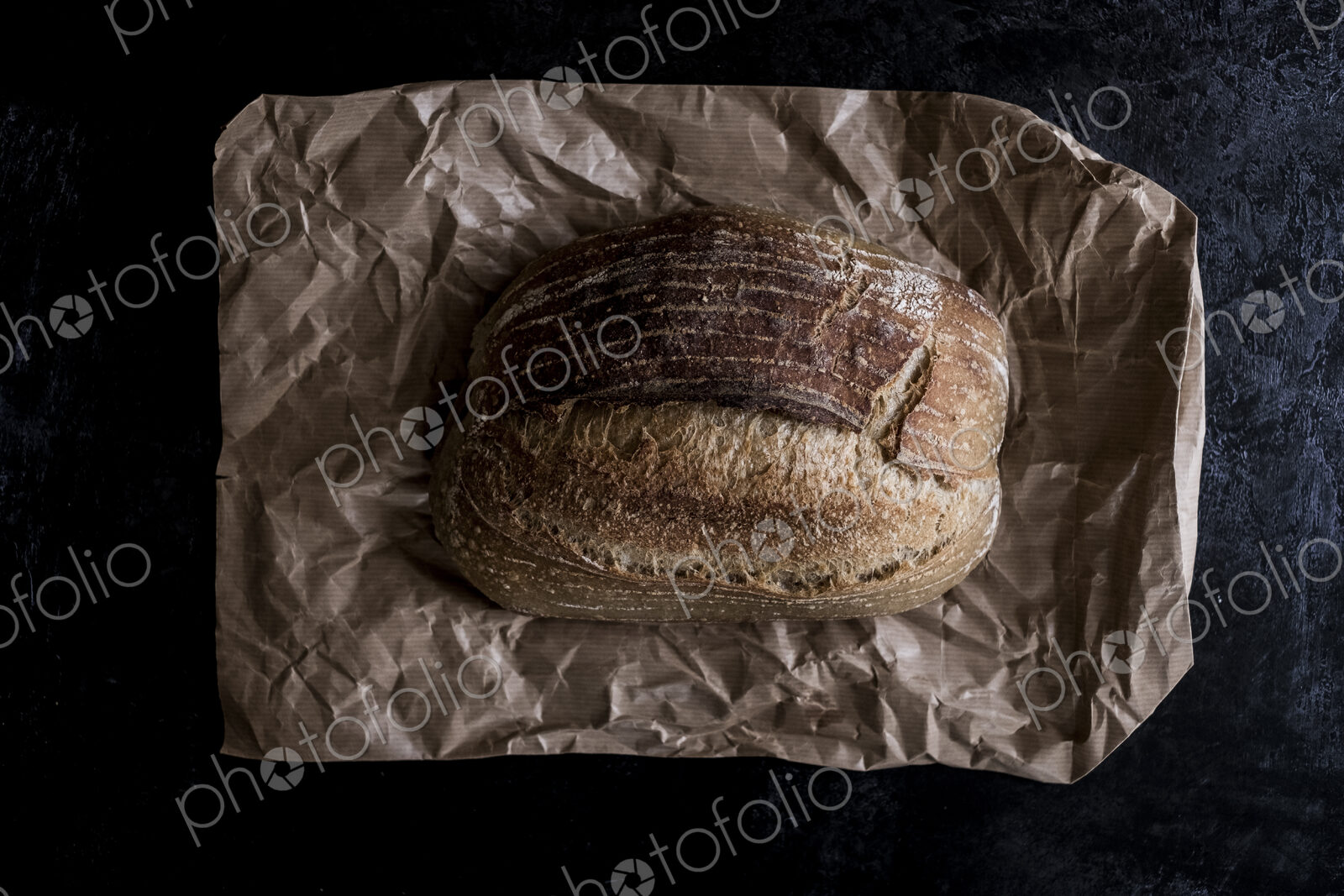 A fresh loaf of baked bread on a brown paper bag.