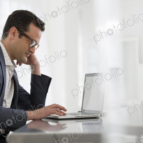 A fresh white building interior, flooded with light. A businessman seated at a table,… A fresh white building interior, flooded with light. A businessman seated at a table,…