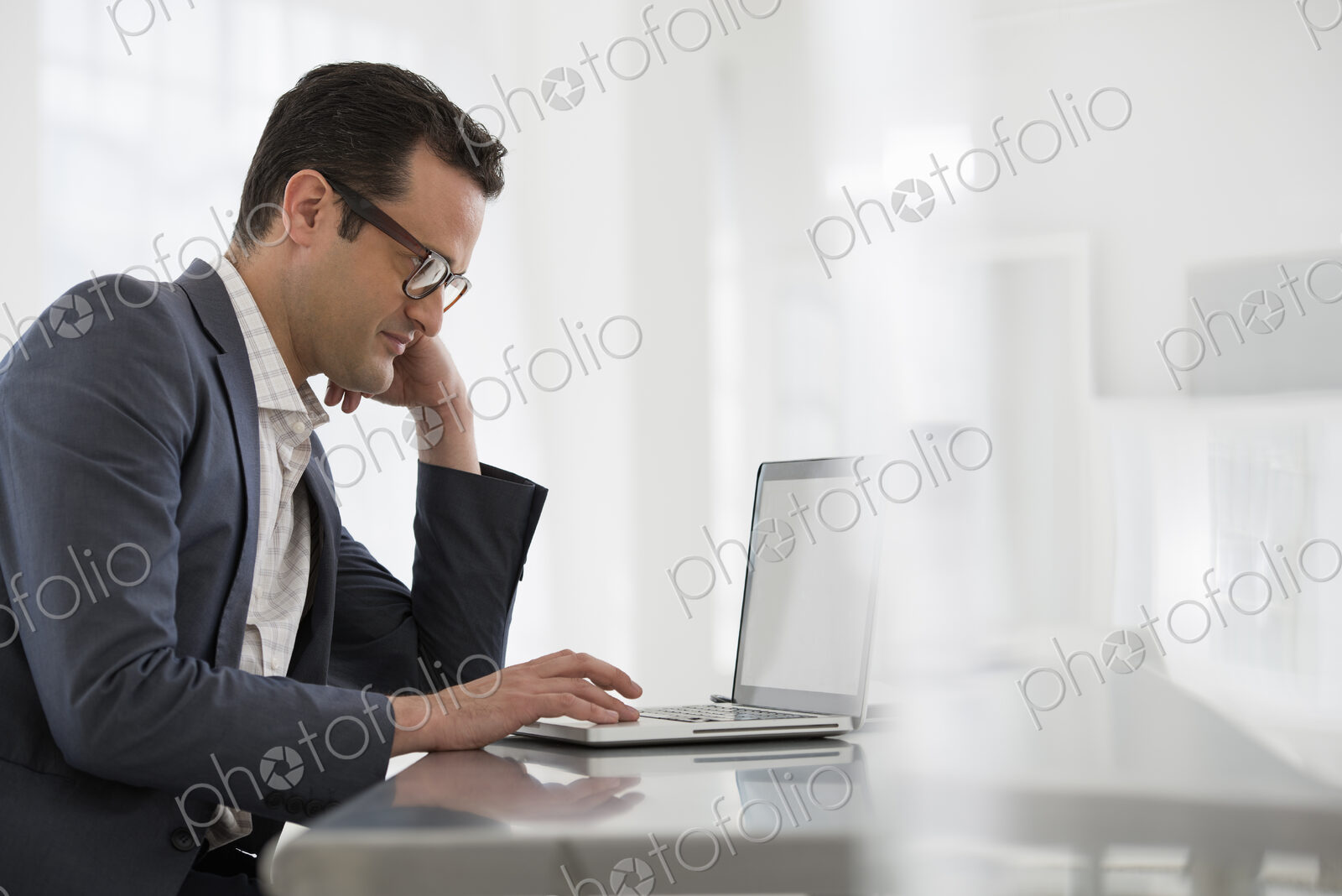 A fresh white building interior, flooded with light. A businessman seated at a table,…