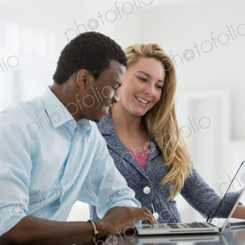 A fresh white building interior, flooded with light. A couple seated side by side at a… A fresh white building interior, flooded with light. A couple seated side by side at a…