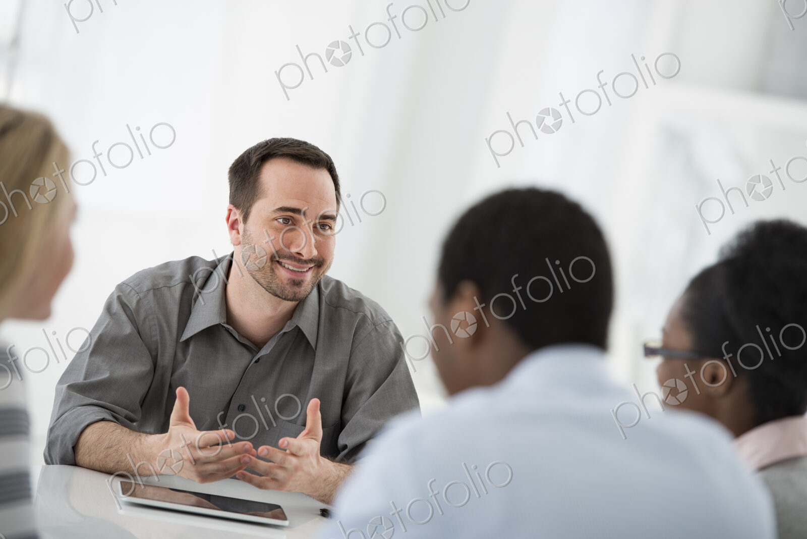 A fresh white building interior, flooded with light. A group of four people, two men…