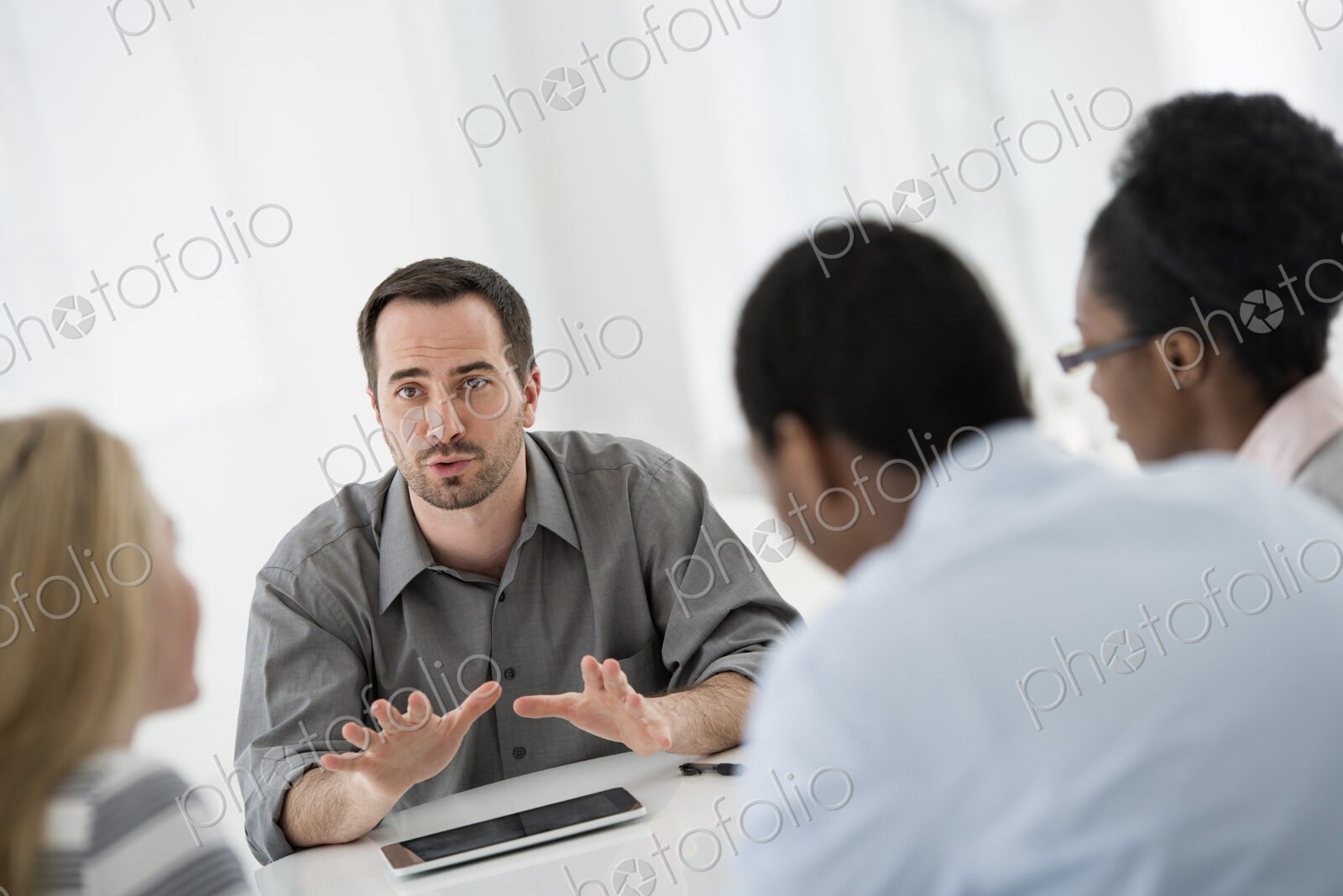 A fresh white building interior, flooded with light. A group of four people, two men…