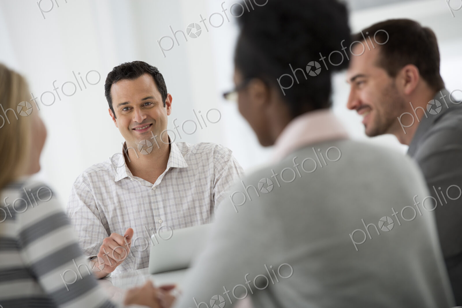 A fresh white building interior, flooded with light. A group of four people, two men…