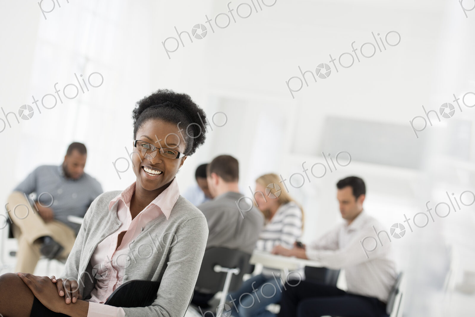 A fresh white building interior, flooded with light. A group of people meeting. One…