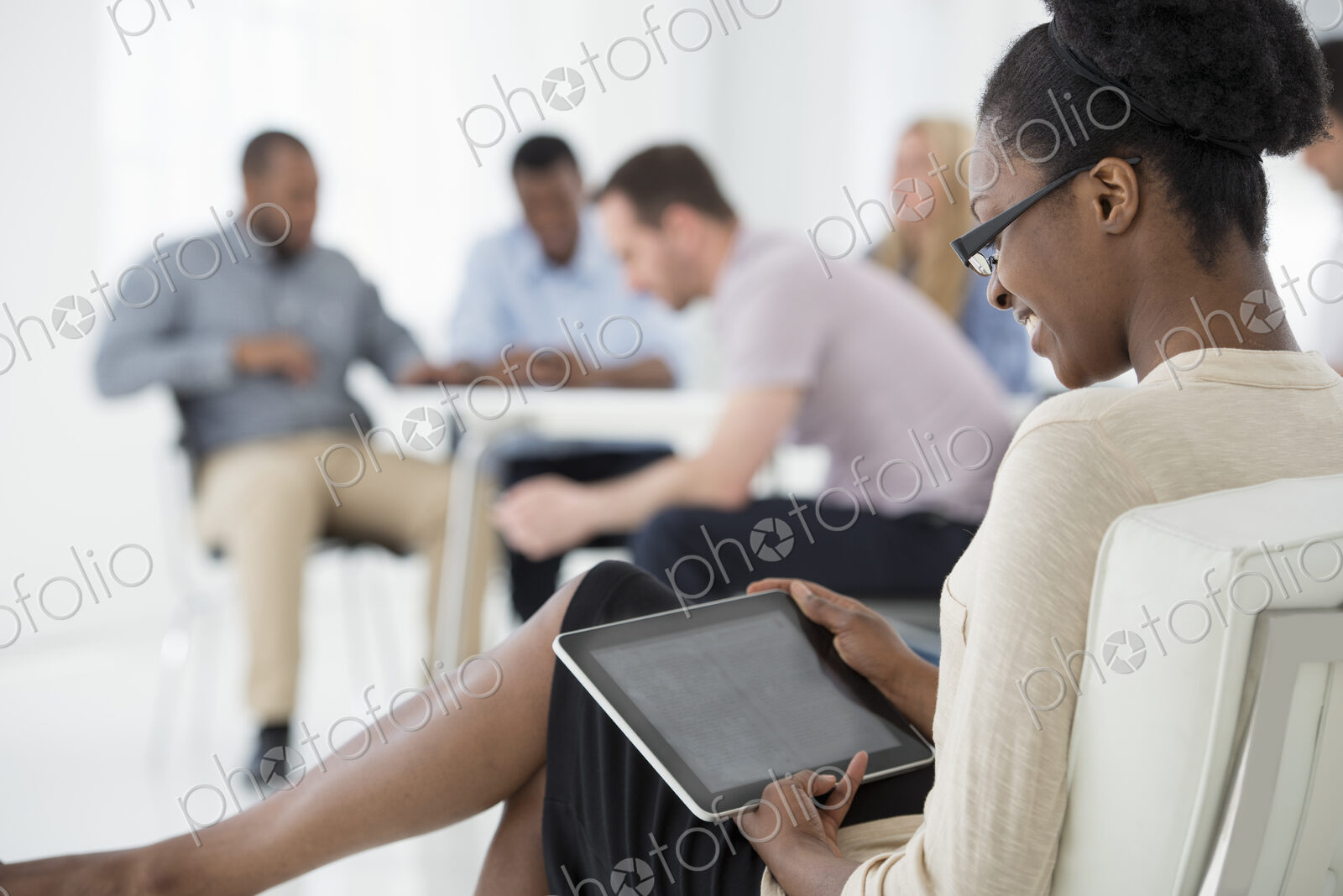 A fresh white building interior, flooded with light. A group of people meeting. One…