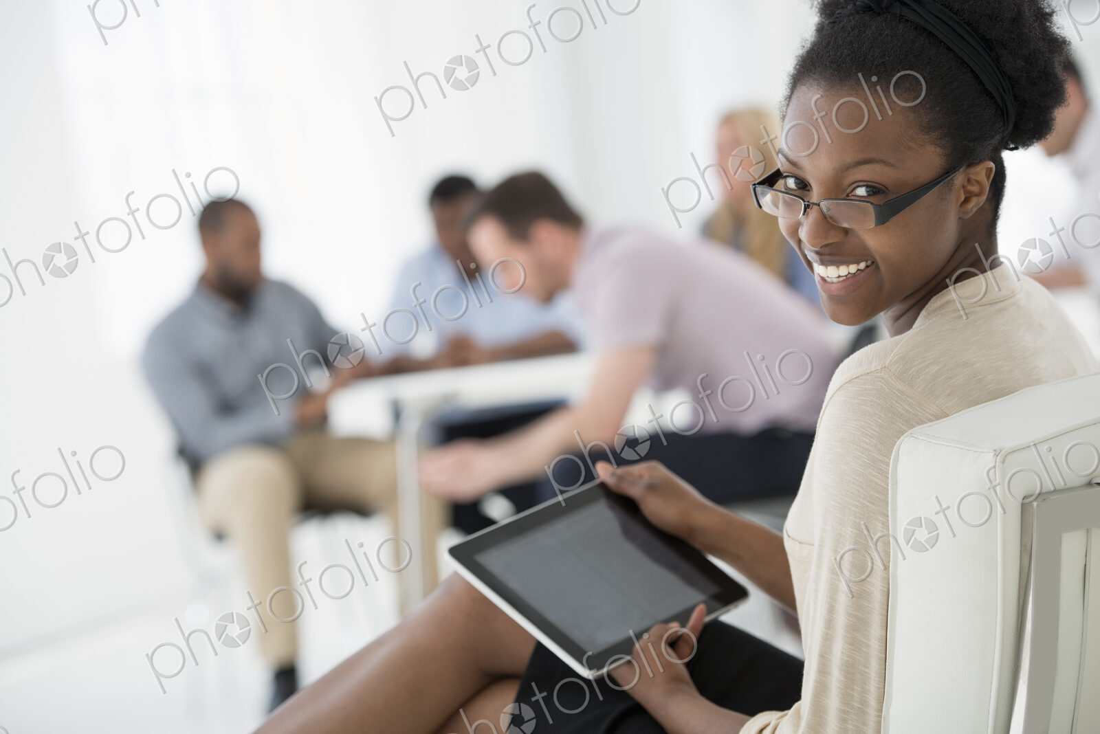 A fresh white building interior, flooded with light. A group of people meeting. One…