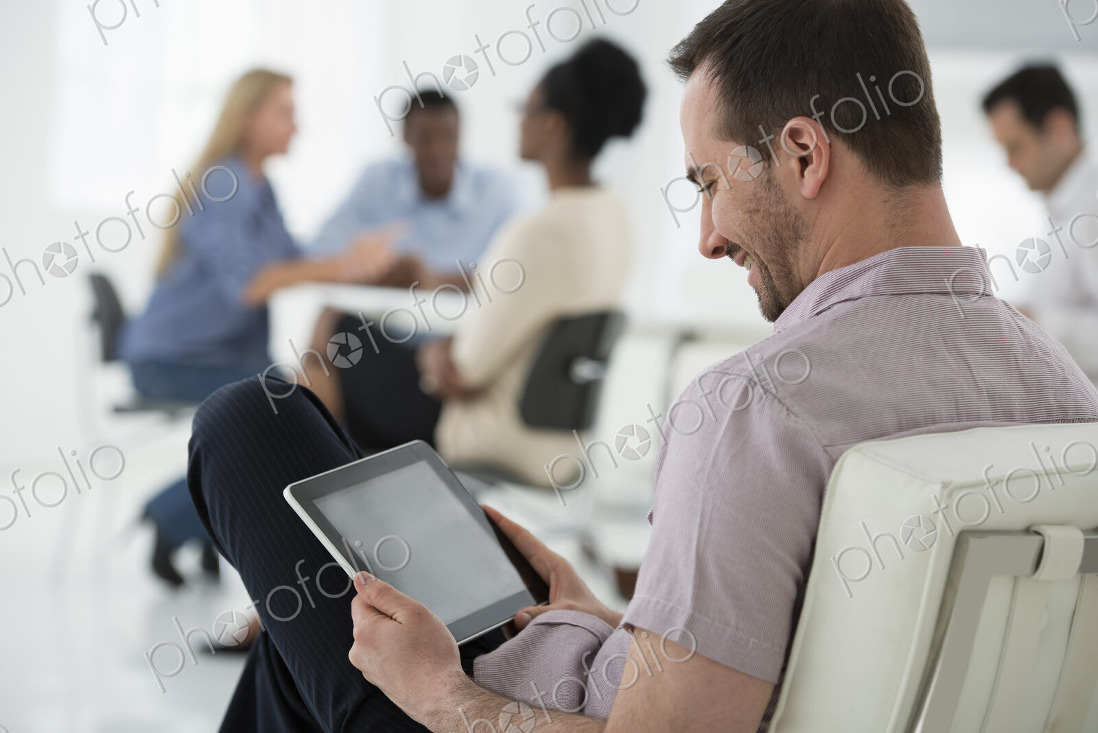 A fresh white building interior, flooded with light. A group of people meeting. One…