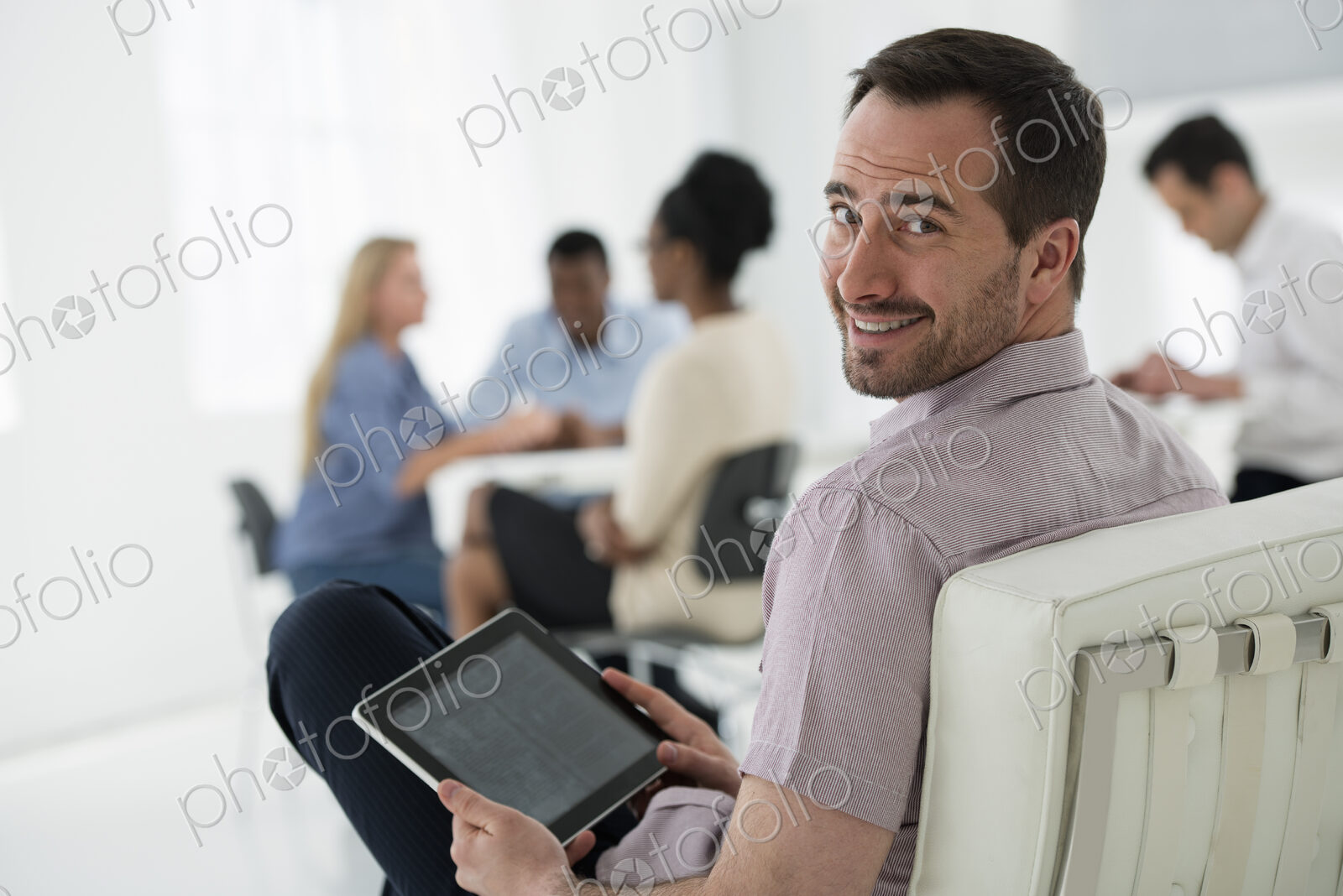 A fresh white building interior, flooded with light. A group of people meeting. One…