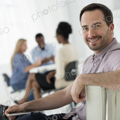 A fresh white building interior, flooded with light. A group of people meeting. One… A fresh white building interior, flooded with light. A group of people meeting. One…