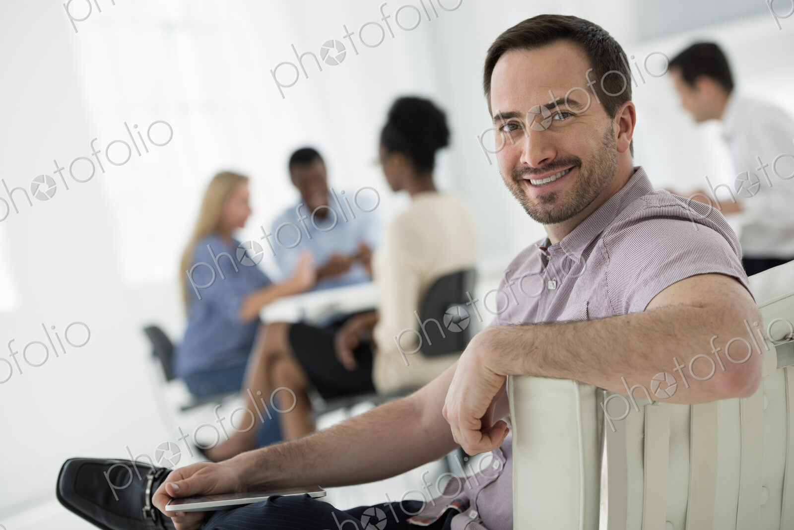 A fresh white building interior, flooded with light. A group of people meeting. One…