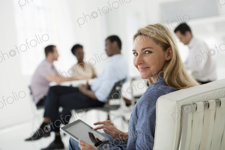 A fresh white building interior, flooded with light. A group of people meeting. One…