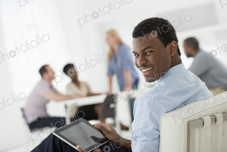 A fresh white building interior, flooded with light. A group of people meeting. One…