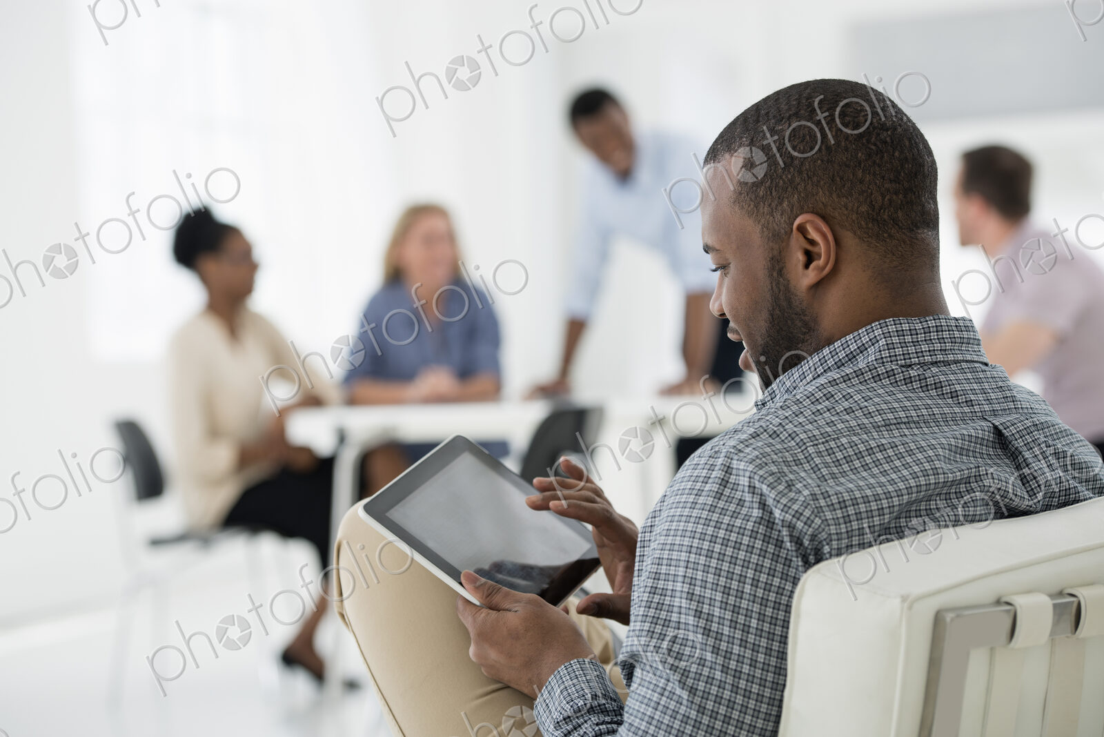 A fresh white building interior, flooded with light. A group of people meeting. One…