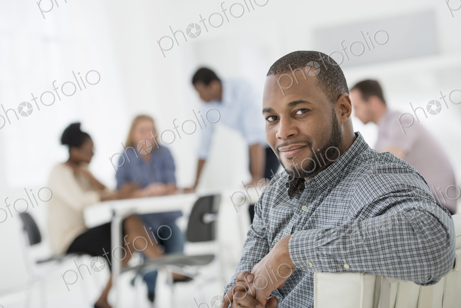 A fresh white building interior, flooded with light. A group of people meeting. One…