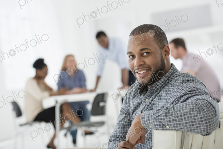 A fresh white building interior, flooded with light. A group of people meeting. One…