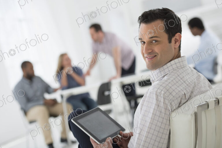 A fresh white building interior, flooded with light. A group of people meeting. One…
