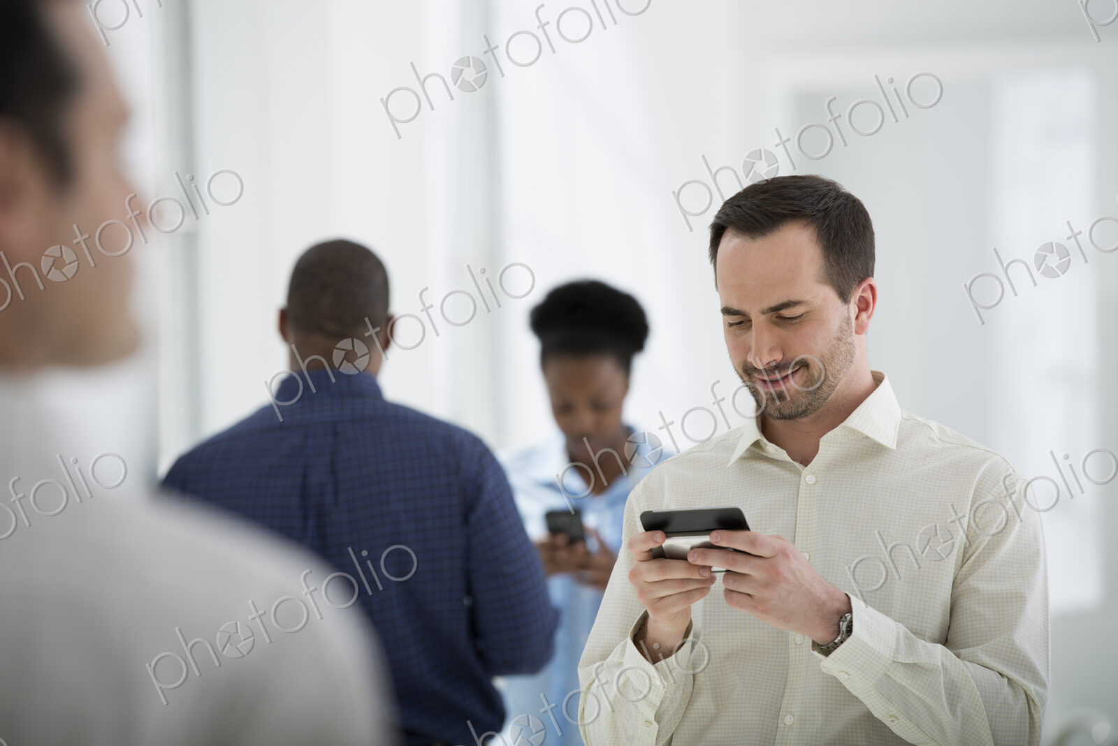 A fresh white building interior, flooded with light. A group of people, one man using…