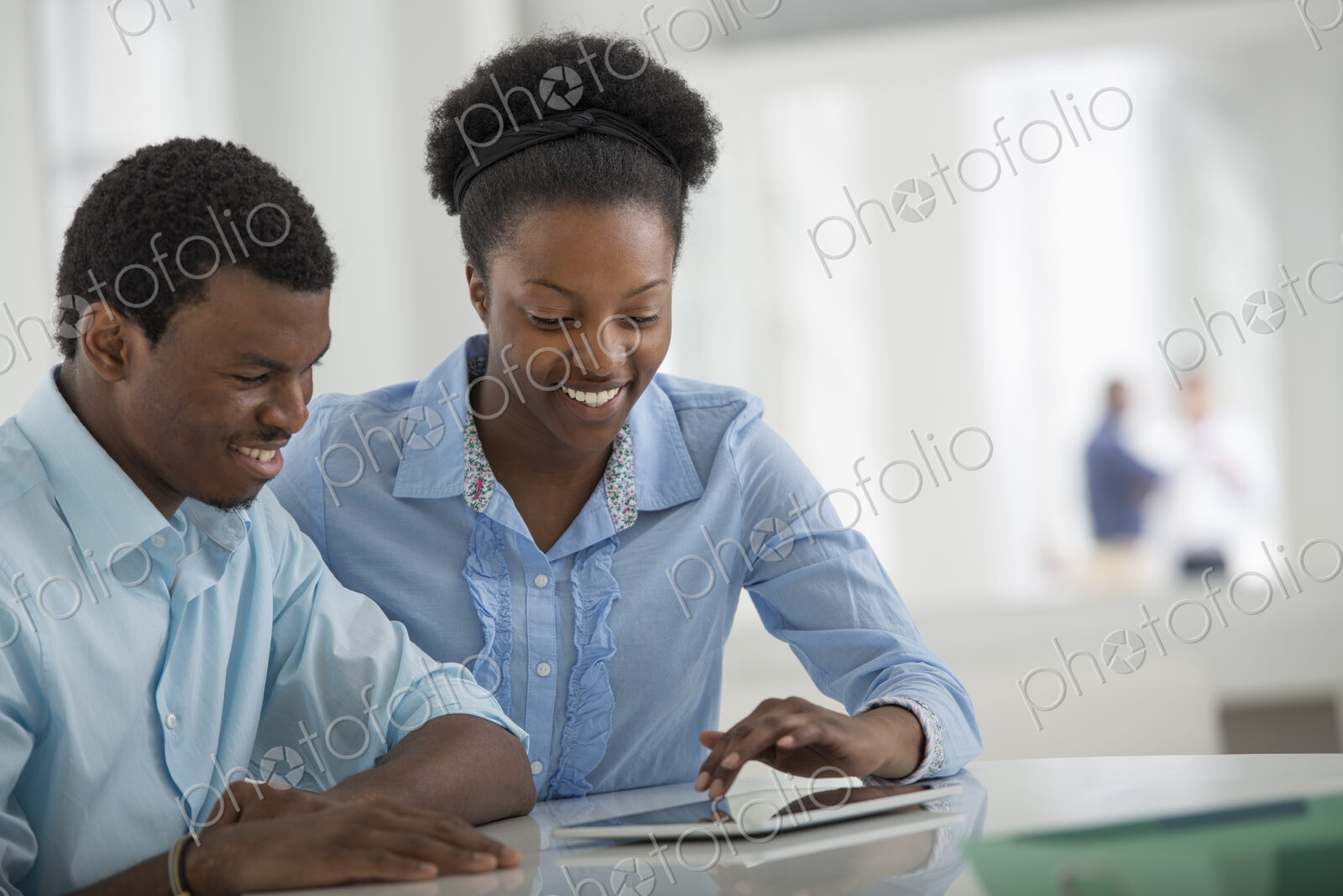 A fresh white building interior, flooded with light. A man and woman sitting side by…